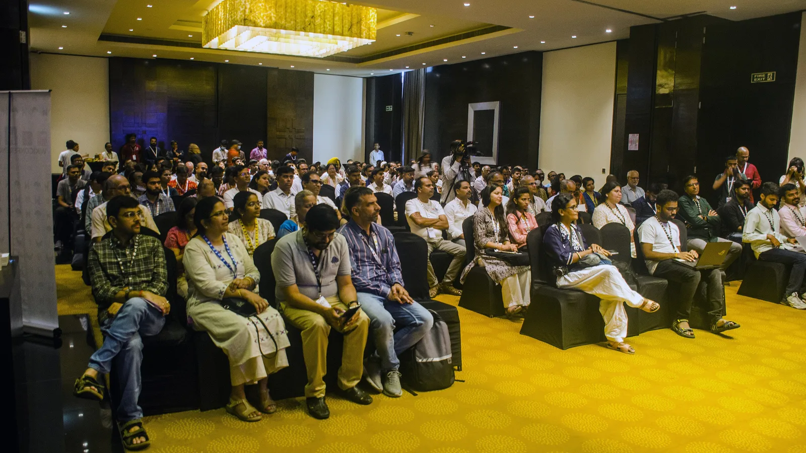 Delegates wearing lanyards seated in a hotel conference hall during a session in Hyderabad