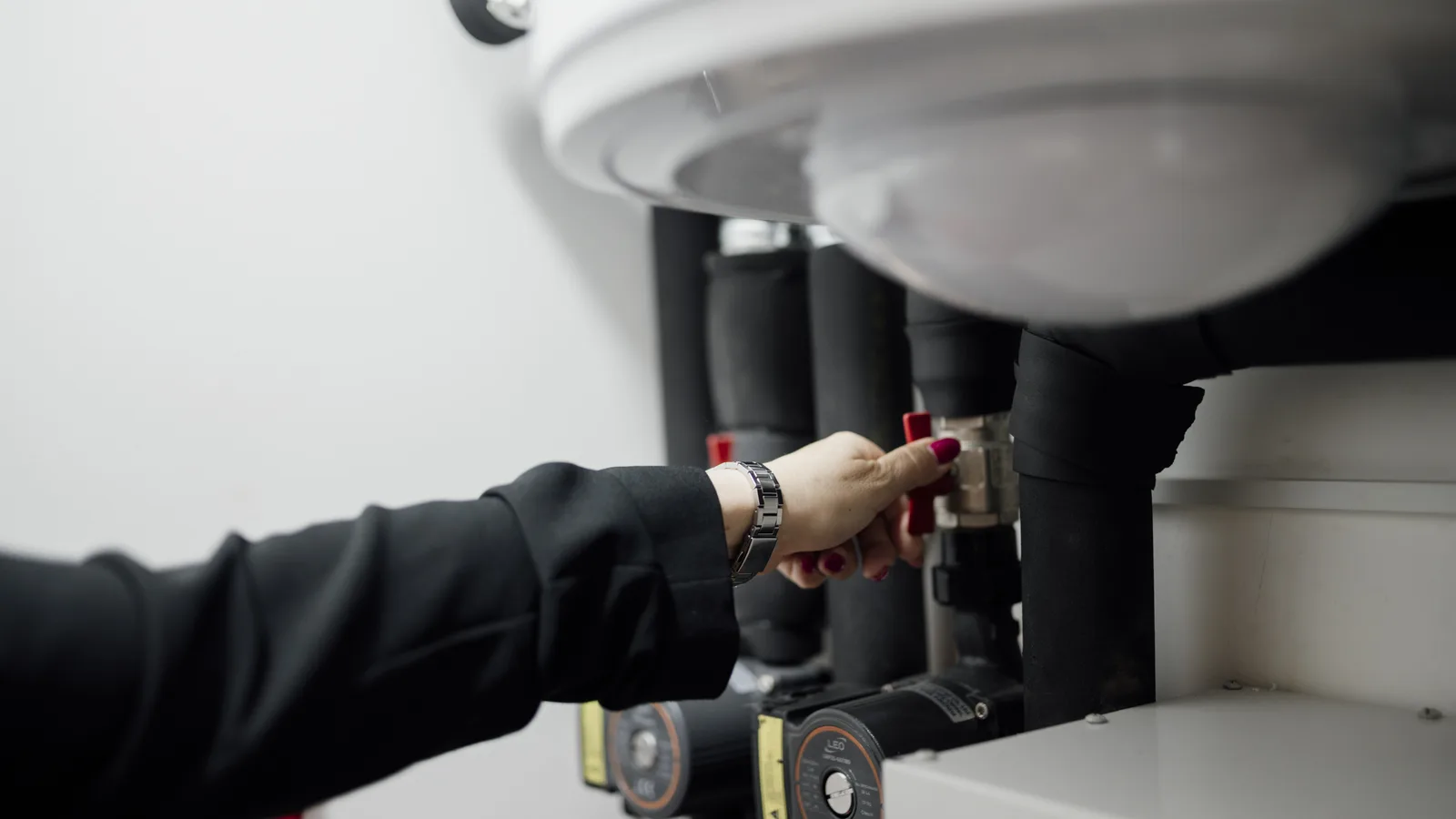 A technician turning a valve on pumps in a plant room during a routine maintenance task