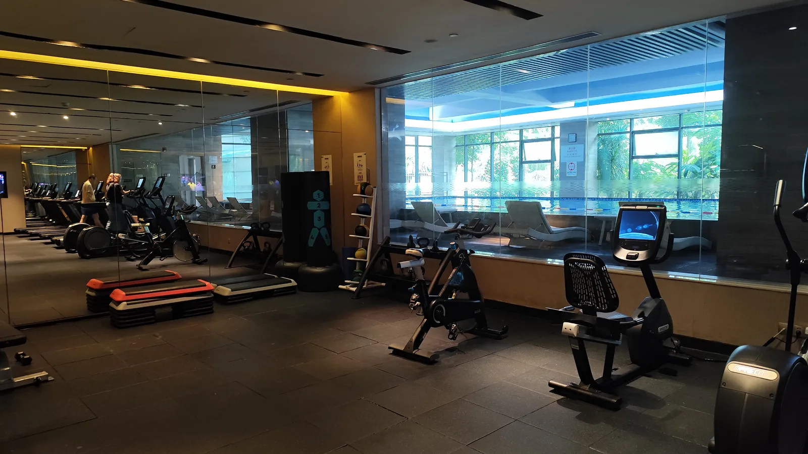 Fitness centre with exercise bikes, step platforms and treadmills beside a glass wall