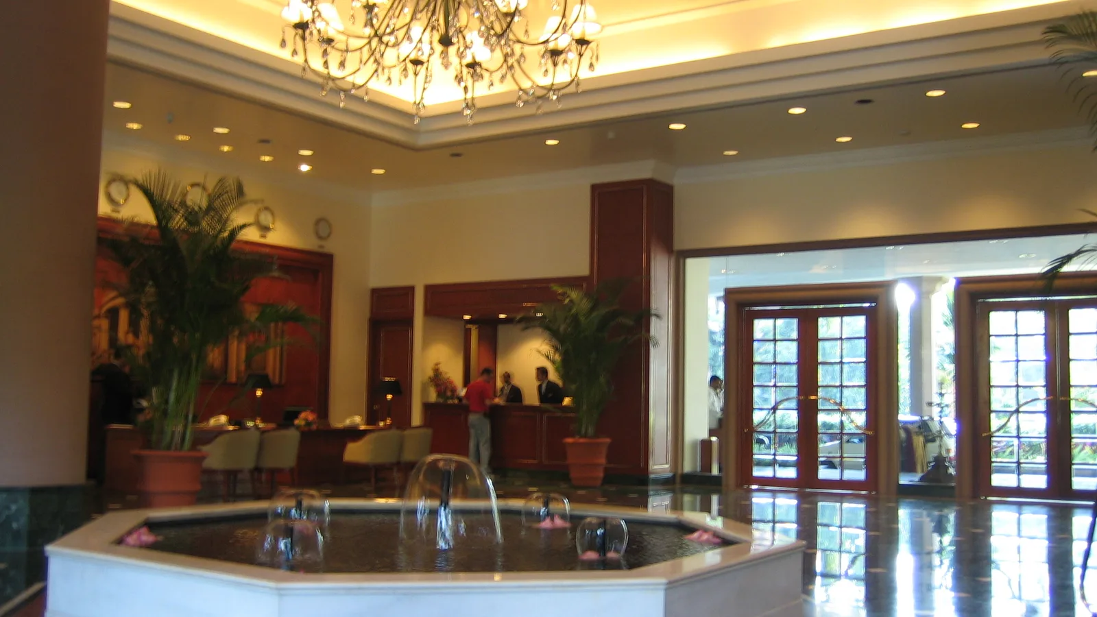 Hotel lobby in Bangalore with a guest at the front desk, a chandelier and a fountain