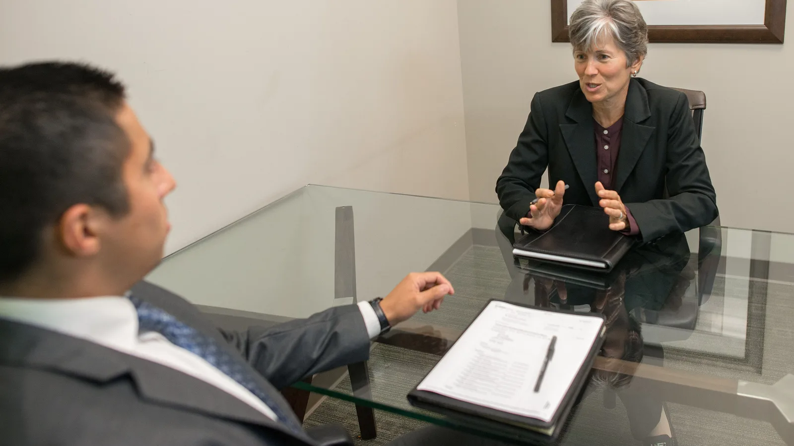 HR manager interviewing a job candidate across a glass table, part of the hiring process HRMS software manages