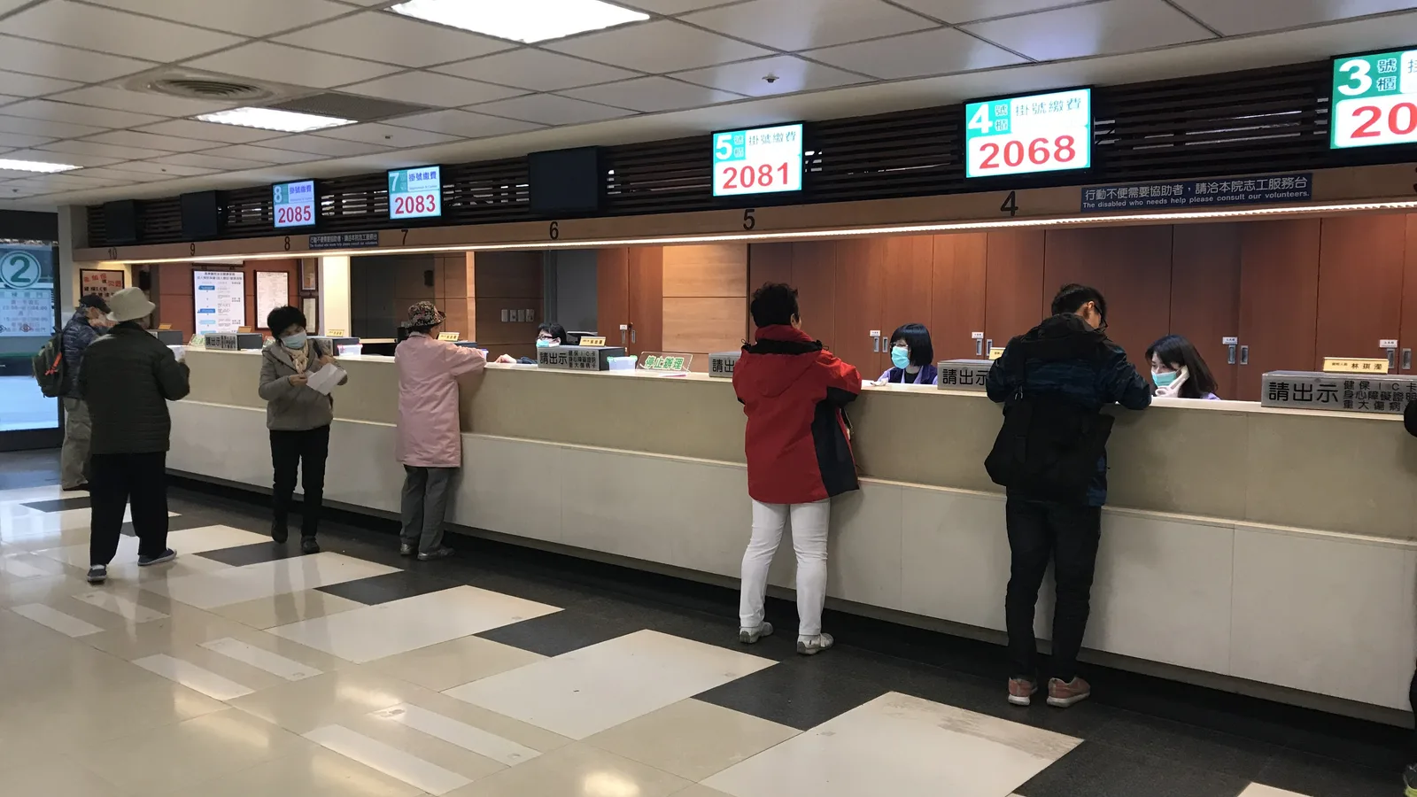 Patients queuing at hospital registration and cashier billing counters with token number displays