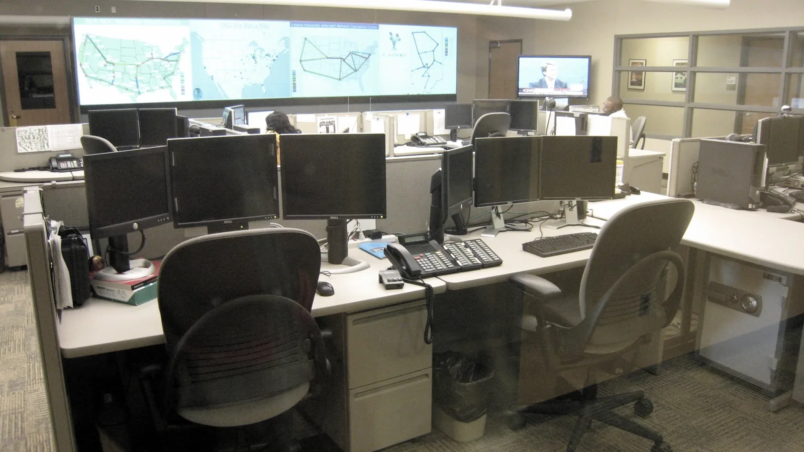 Network operations centre with monitoring desks and a wall of status screens