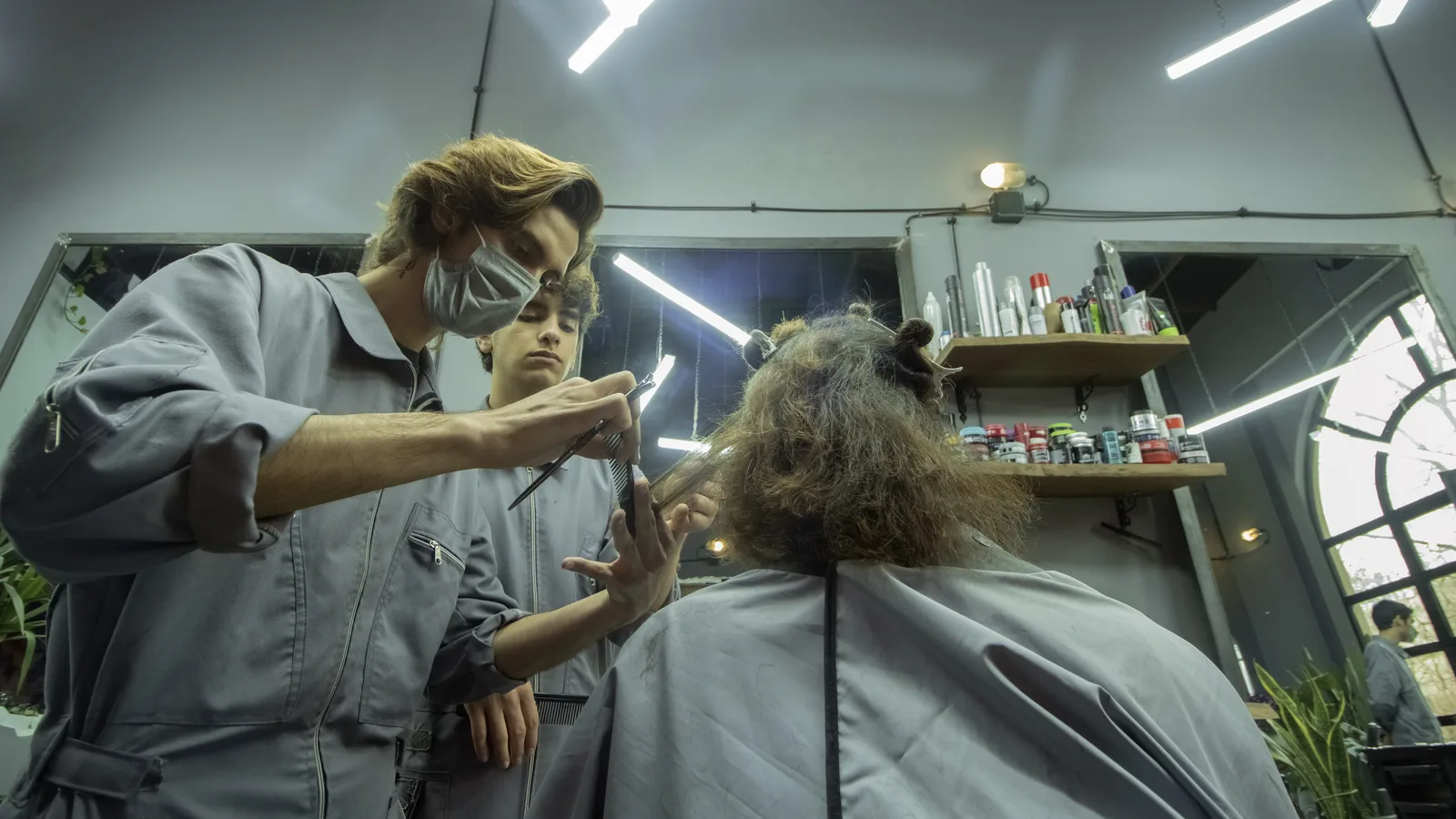 A stylist cutting a client’s hair in a modern salon, the day-to-day work salon booking and billing software supports