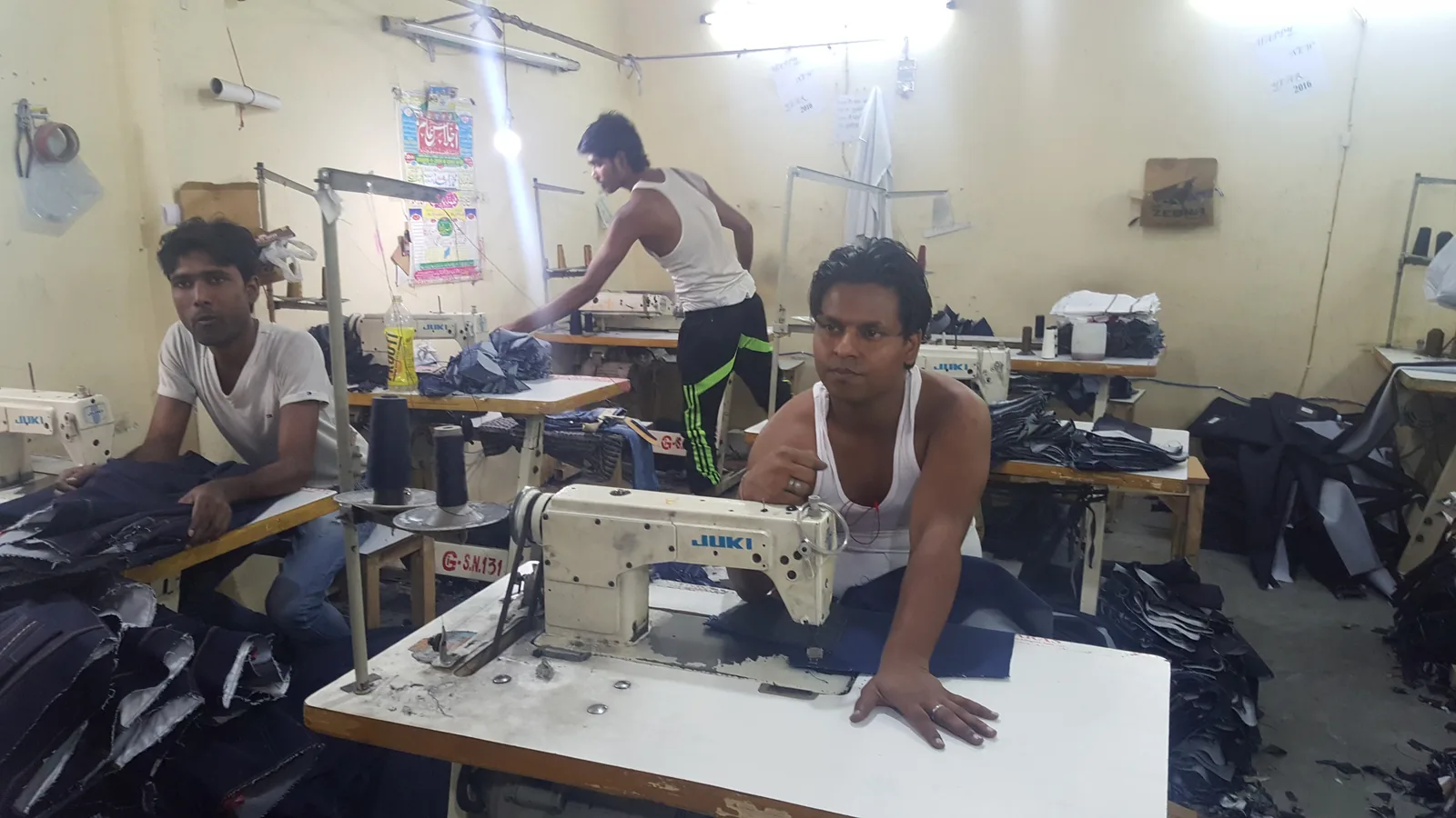 Garment workers at sewing machines in a small denim factory in Karawal Nagar, Delhi