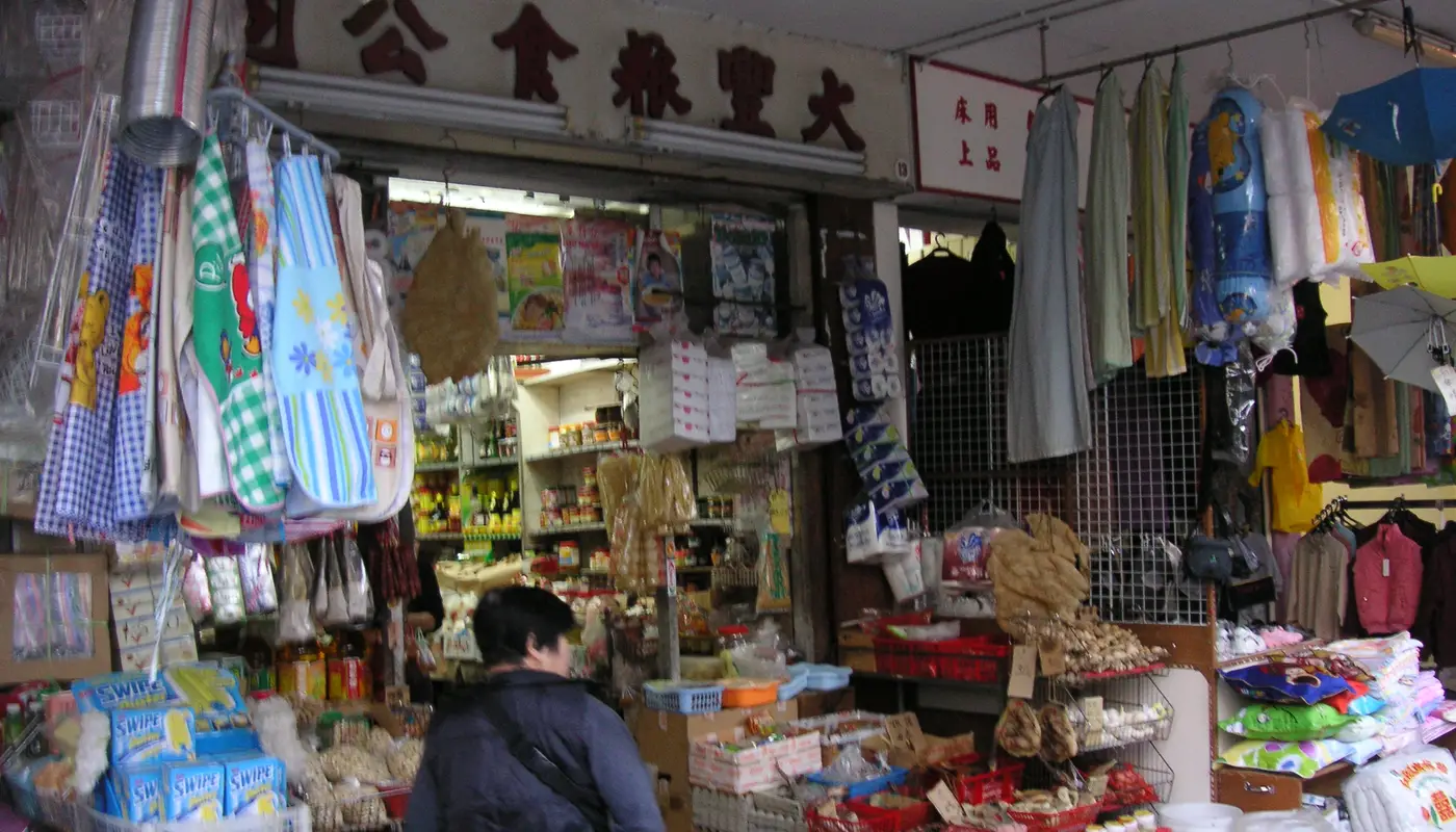A retail shop owner sending WhatsApp order updates to customers from a phone at the counter